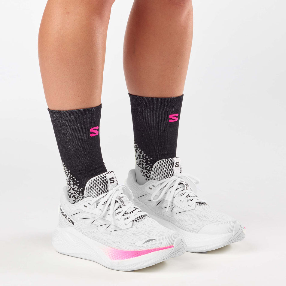 A model wearing a pair of Salomon Women's Aero Glide 4 Running Shoes in the White/White/Black colourway.