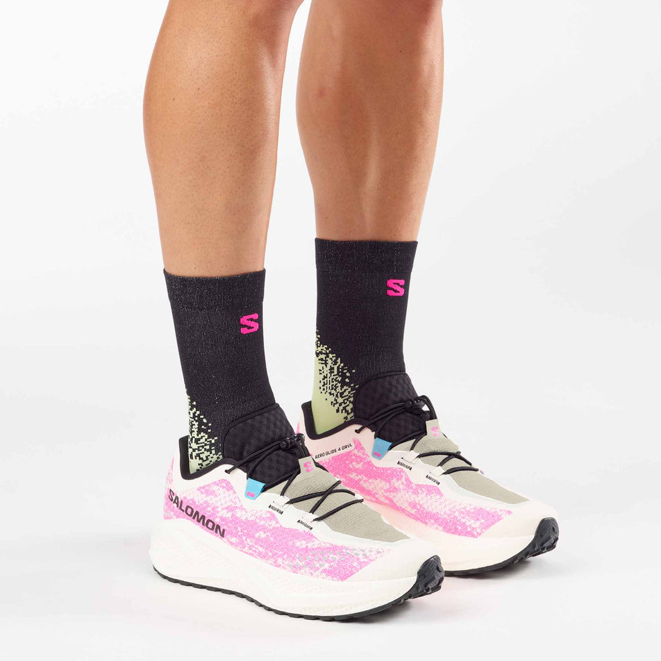 A model wearing a pair of Salomon Men's Aero Glide 4 GRVL Running Shoes in the Vanilla Ice/Knockout Pink/Black colourway.
