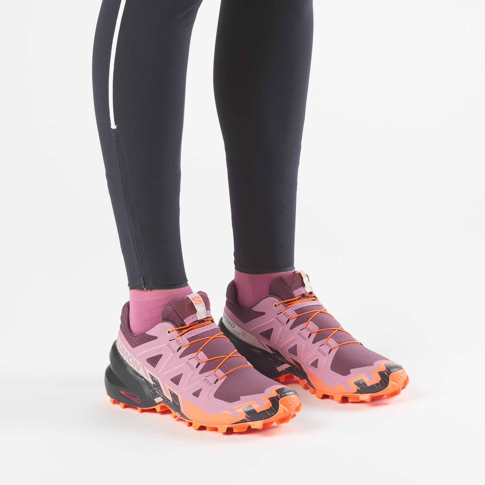 A model wearing a pair of Salomon Women's Speedcross 6 Trail Running Shoes in the Huckleberry/Dusky Orchid colourway.