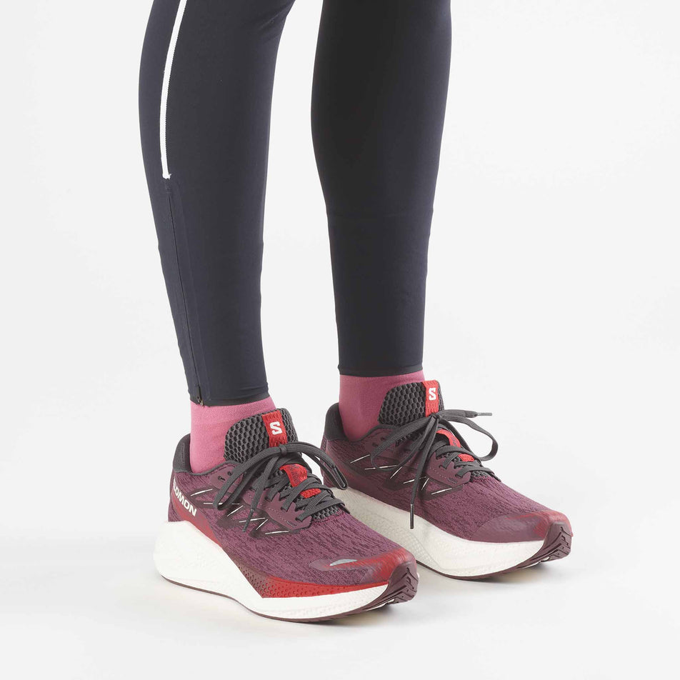 A model wearing a pair of Salomon Women's Aero Glide 4 Running Shoes in the Huckleberry/Vanilla Ice colourway.