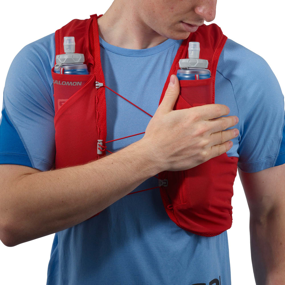 Front view of a model wearing a Salomon Unisex ADV Skin 5 Running Vest in the Goji Berry/Ebony colourway, with flasks included. (7991875502242)