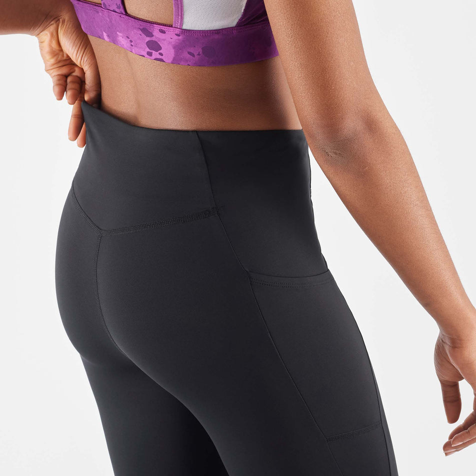 A model demonstrating the waistband stretch on a pair of Salomon Women's Cross Warm 28