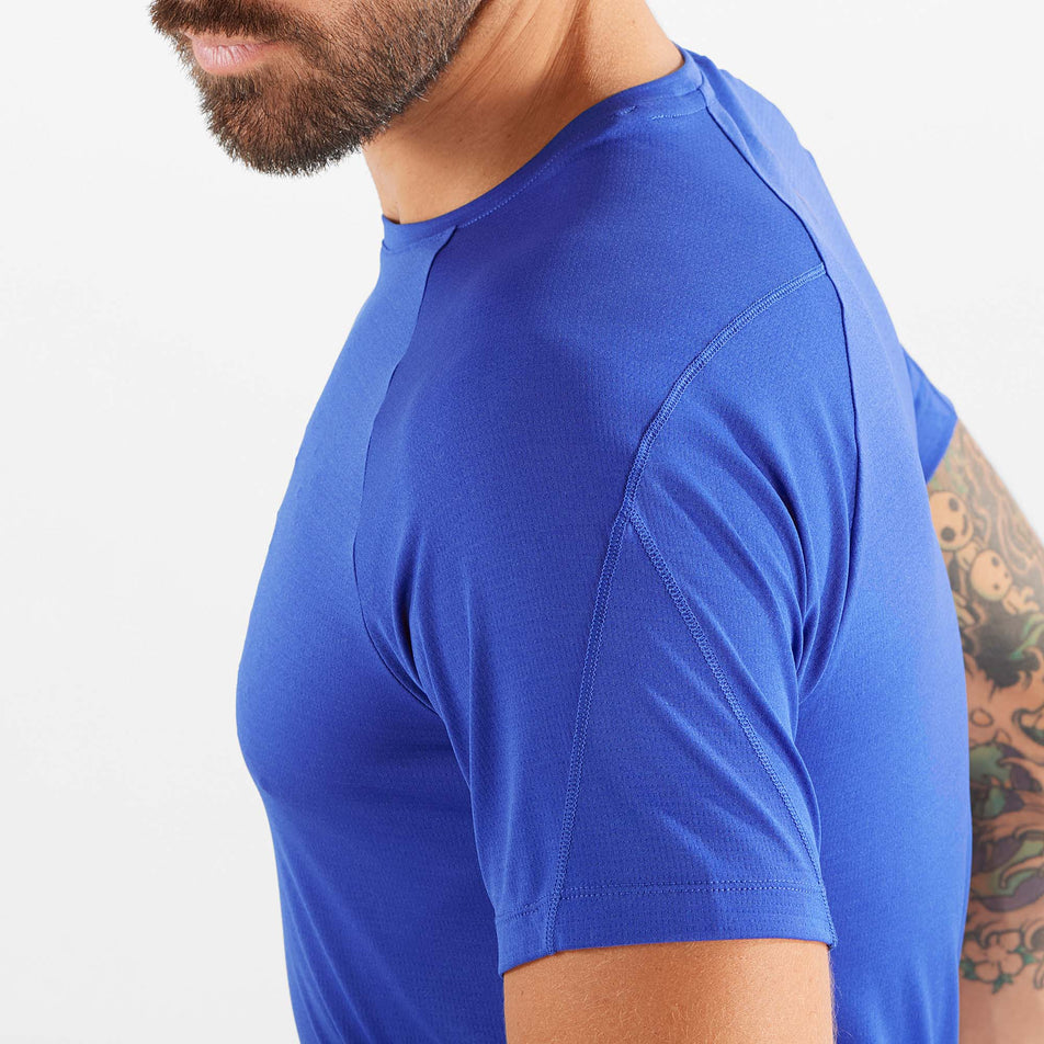 Close-up side view of a model wearing a Salomon Men's Cross Run Short Sleeve T-Shirt in the Surf The Web colourway. Upper half of the t-shirt is visible.  (8008549040290)