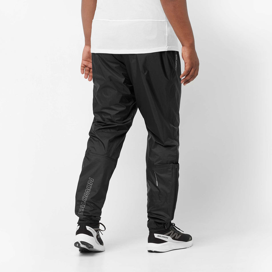 Back view of a model wearing a pair of Salomon Unisex Bonatti Waterproof Pants in the Deep Black colourway (8071099220130)