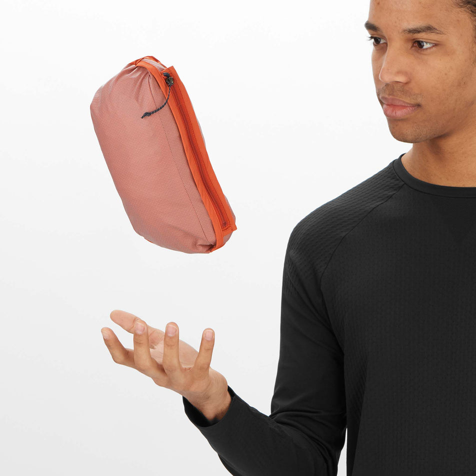 A model demonstrating that a Salomon Men's Bonatti Trail Jacket can be packed into its pocket.  (8008561098914)