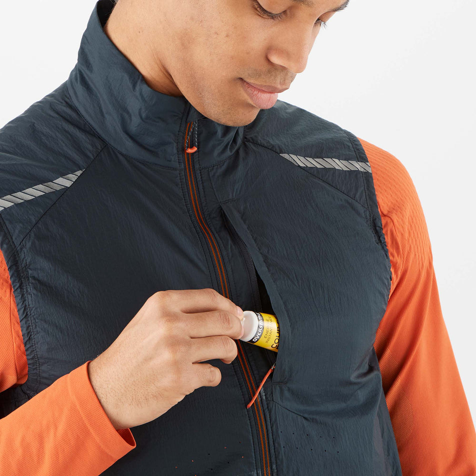 A model demonstrating that an energy gel can be stored in the chest pocket of a Salomon Men's Sense Flow Vest (8071113769122)