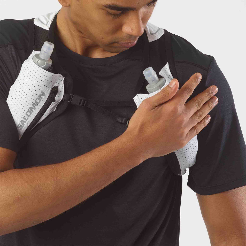A model pressing one of the soft flasks on the front of a Salomon Unisex Pulse 2 with flasks. (8008842510498)