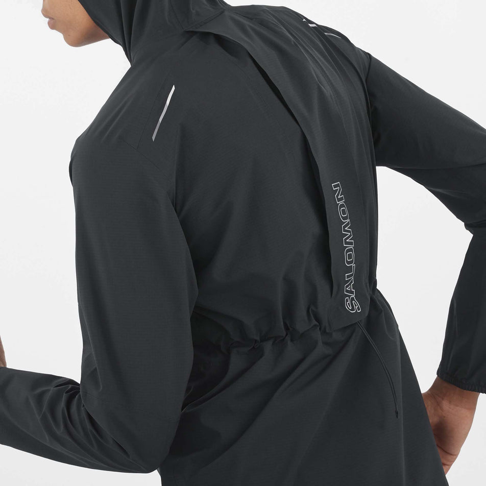 Close-up back view of a model wearing a Salomon Women's Bonatti Trail Jacket in the Deep Black colourway. Model is in a running pose. (8157861019810)