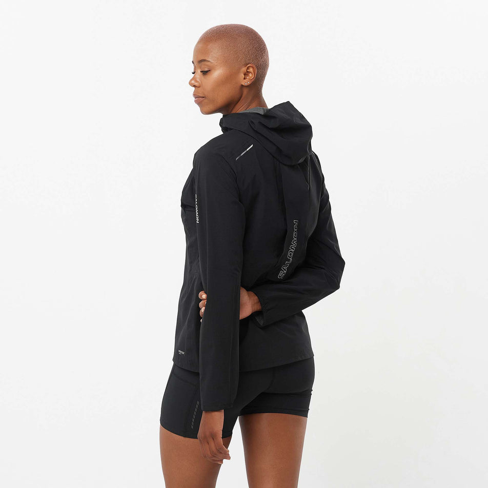 Back view of a model wearing a Salomon Women's Bonatti Trail Jacket in the Deep Black colourway. Model is also wearing Salomon shorts. (8157861019810)