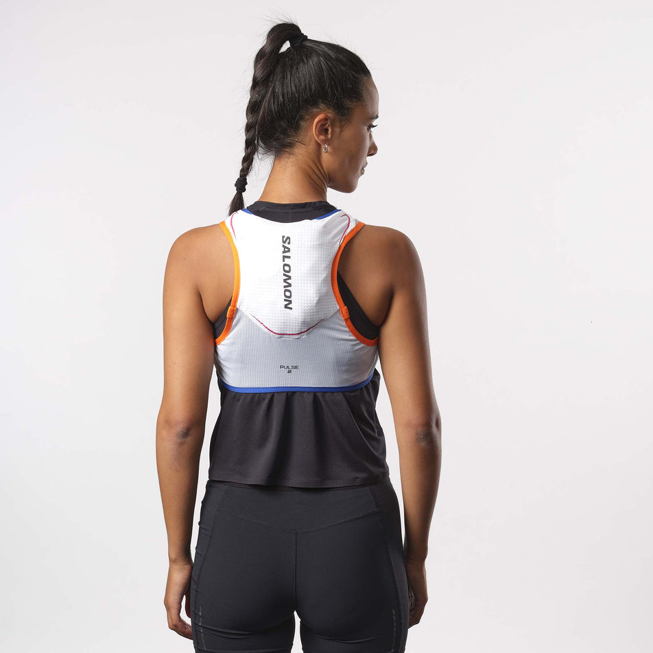 Back view of a model wearing a Salomon Unisex Pulse 2 Running Vest with flasks included, in the Unisex Pulse 2 Running Vest with flasks included. WHITE/Surf The Web/DRAGON FIRE colourway. Model is also wearing a running top and shorts. (8151581458594)