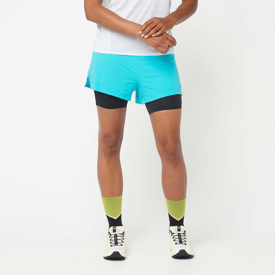 Front view of a model wearing a pair of Salomon Women's Sense Aero 2in1 Shorts in the Peacock Blue colourway. Model is also wearing Salomon shoes, socks and a t-shirt. (8157883465890)