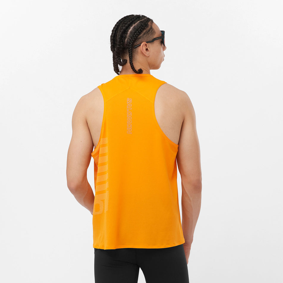 Back view of a model wearing a Salomon Men's Sense Aero GFX Singlet in the Zinnia/White colourway. Model is also wearing sunglasses and leggings. (8311786799266)