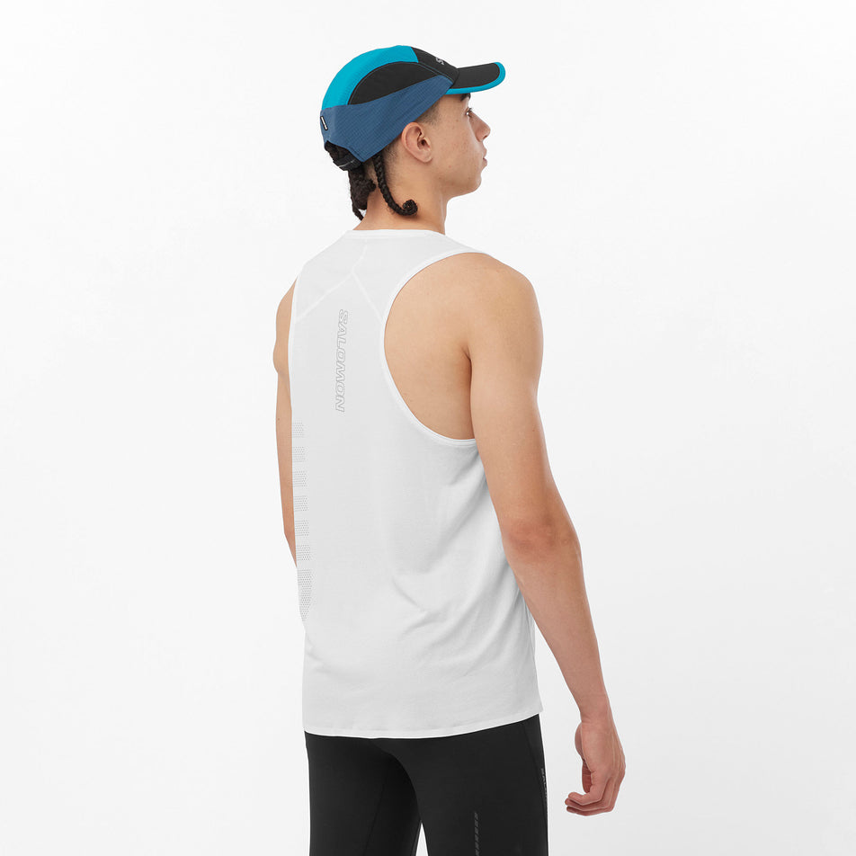 Back view of a model wearing a Salomon Men's Sense Aero GFX Singlet in the White/Peacock Blue colourway. Model is also wearing a Salomon cap and leggings. (8311799152802)