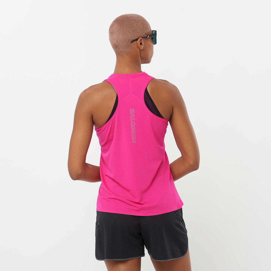 Back view of a model wearing a Salomon Women's Sense Aero Singlet in the Beetroot Purple colourway. Model is also wearing sunglasses and Salomon shorts. (8311884054690)