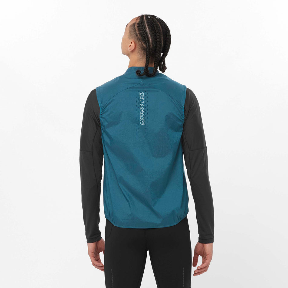Back view of a model wearing a Salomon Men's Sense Aero Wind Vest in the Deep Dive colourway. Model is also wearing a Salomon long sleeve top and Salomon tights. (8157820977314)