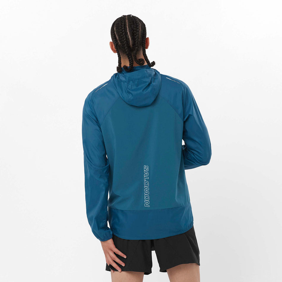Back view of a model wearing a Salomon Men's Cross Wind Jacket in the Deep Dive colourway. Model is also wearing shorts. (8157819568290)