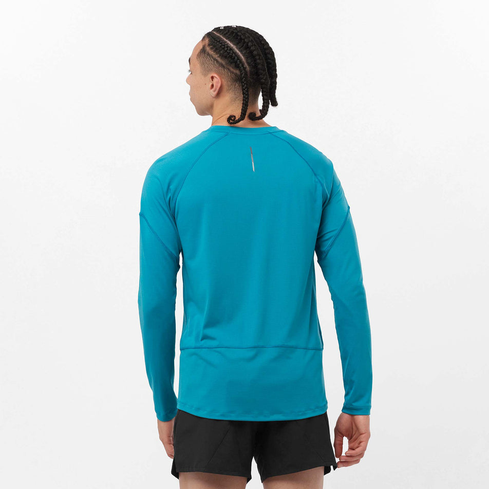 Back view of a model wearing a Salomon Men's Cross Run Long Sleeve T-Shirt in the Tahitian Tide colourway. Model is also wearing shorts. (8157833363618)