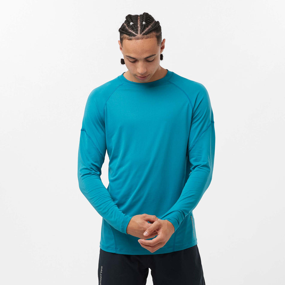 Front view of a model wearing a Salomon Men's Cross Run Long Sleeve T-Shirt in the Tahitian Tide colourway. Model is also wearing shorts. (8157833363618)