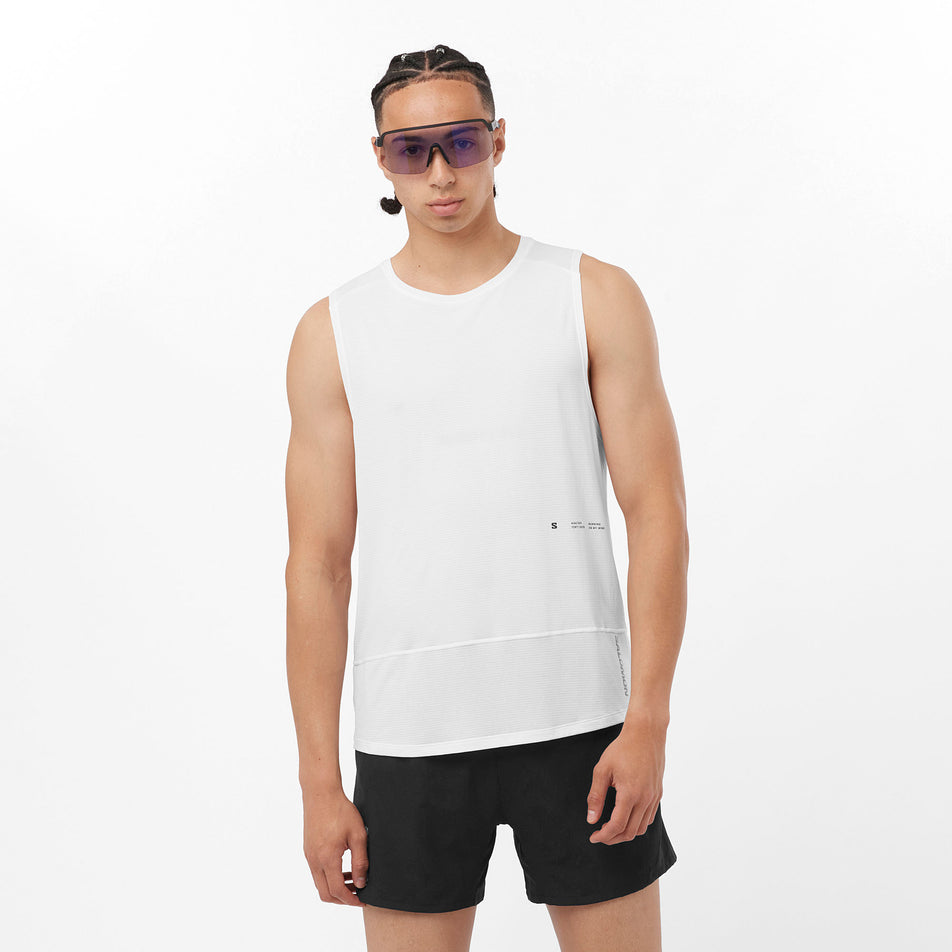 Front view of a model wearing a Salomon Men's Cross Run Tank GFX in the White colourway. Model is also wearing sunglasses and shorts. (8246399729826)