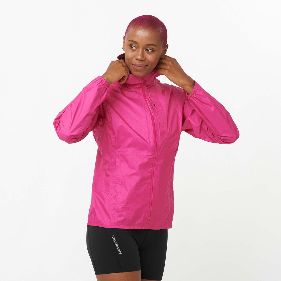 Front view of a model wearing a Salomon Women's Bonatti Waterproof Jacket in the Beetroot Purple colourway. Model is also wearing Salomon shorts. (8157863674018)