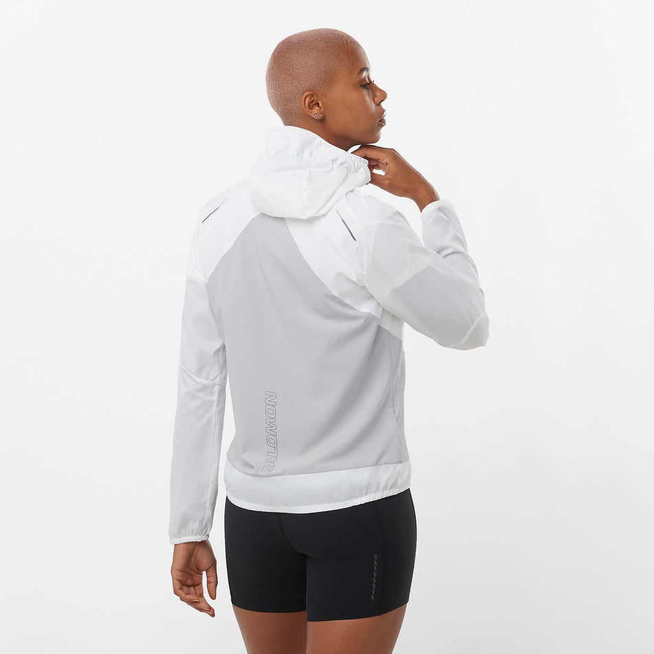 Back view of a model wearing a Salomon Women's Bonatti Cross Wind Jacket in the White/Gray Violet colourway. Model is also wearing Salomon shorts. (8157867016354)