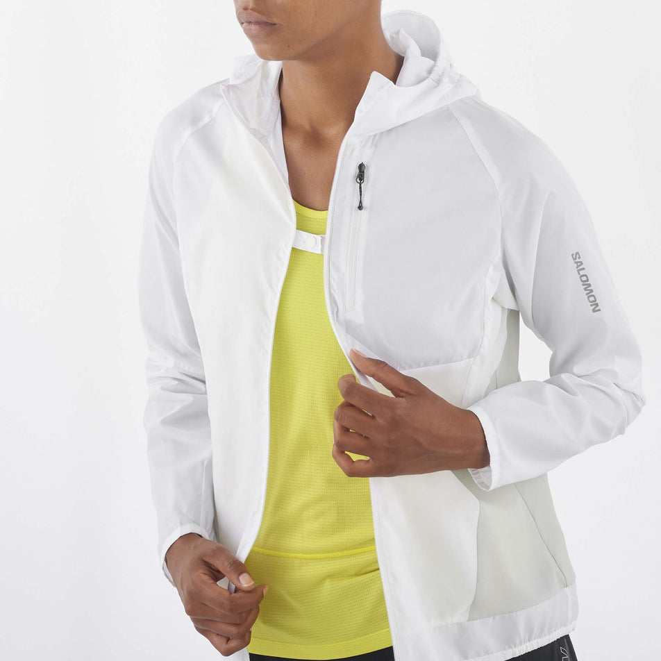 Close-up front view of a model wearing a Salomon Women's Bonatti Cross Wind Jacket in the White/Gray Violet colourway. Model has the jacket unzipped, but the front sides are attached to each other via the fastener at the chest. (8157867016354)
