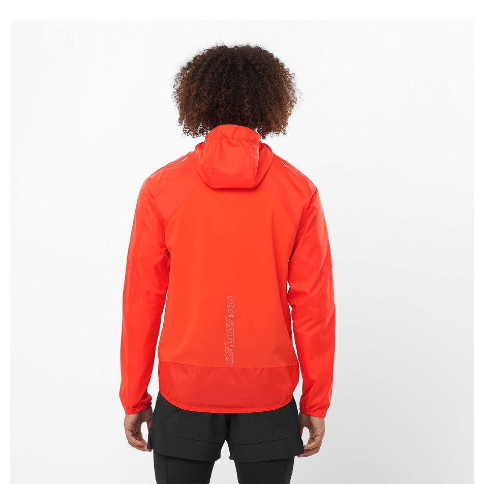 Back view of a model wearing a Salomon Men's Bonatti Cross Wind Jacket Hoodie in the Cherry Tomato colourway. Model is also wearing legwear. (8466593087650)