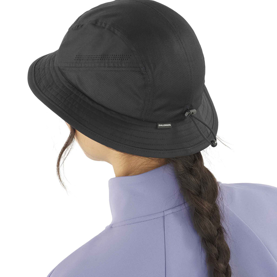 Back view of a model wearing the Salomon Unisex SHKout Bucket Hat in the Deep Black colourway. (8577875476642)