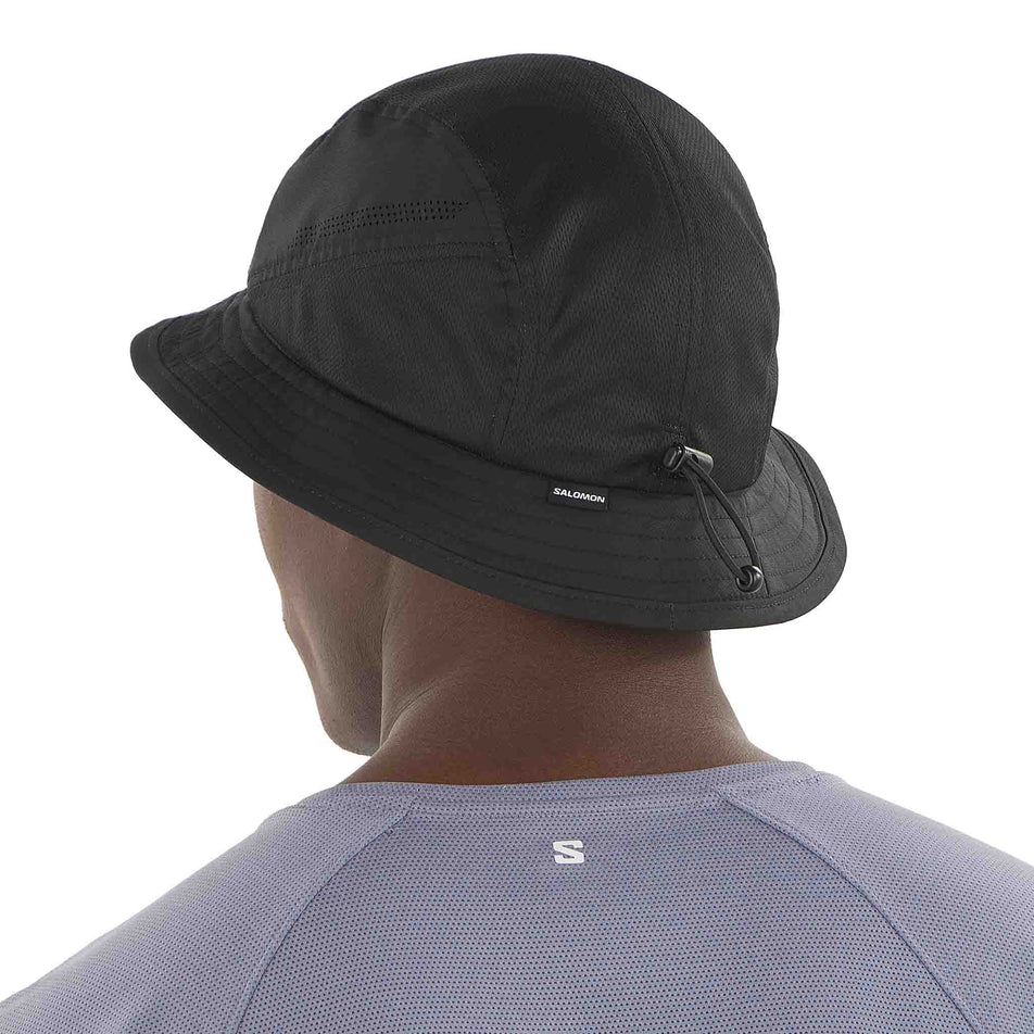 Back view of a model wearing the Salomon Unisex SHKout Bucket Hat in the Deep Black colourway. (8577875476642)