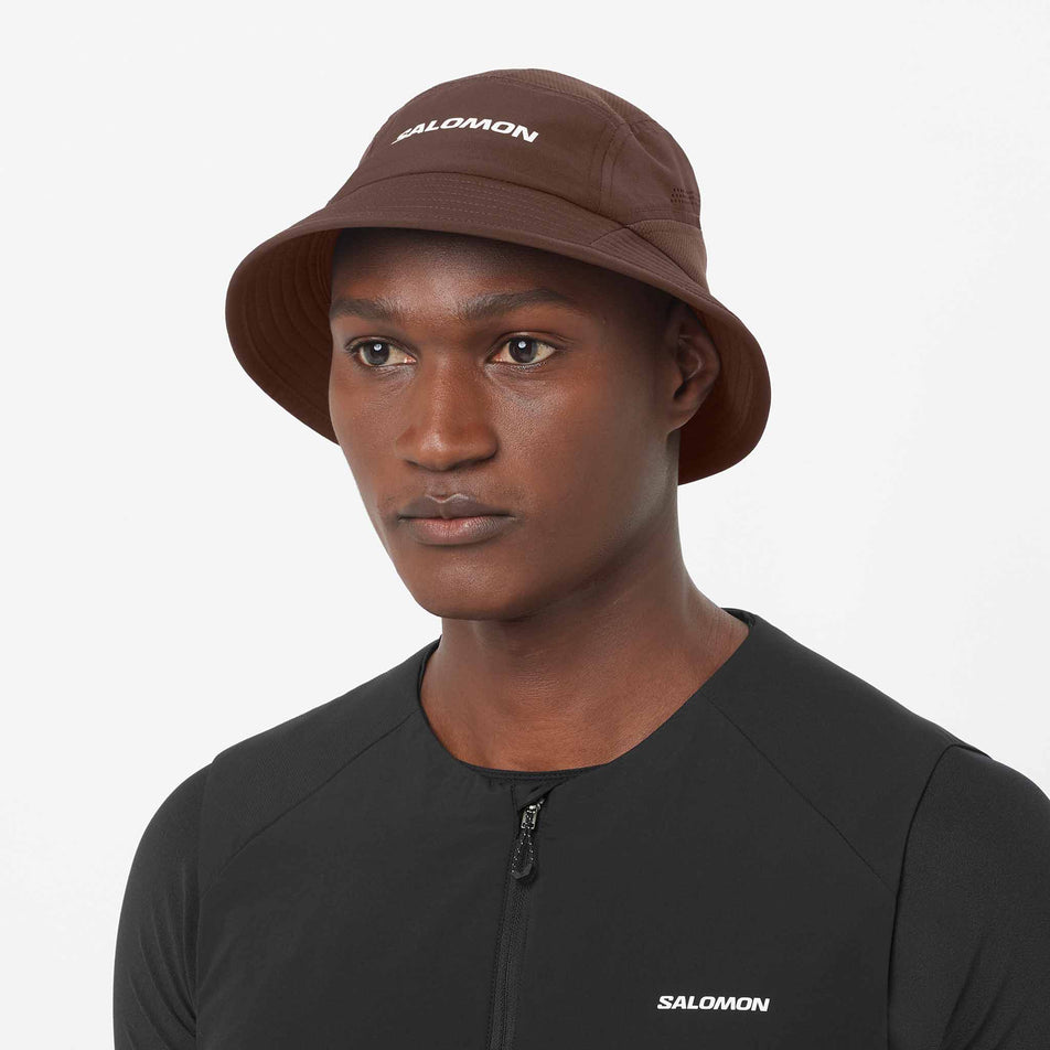 Front view of a model wearing the Salomon Unisex Shakeout Bucket Hat in the Coffee Bean colourway.