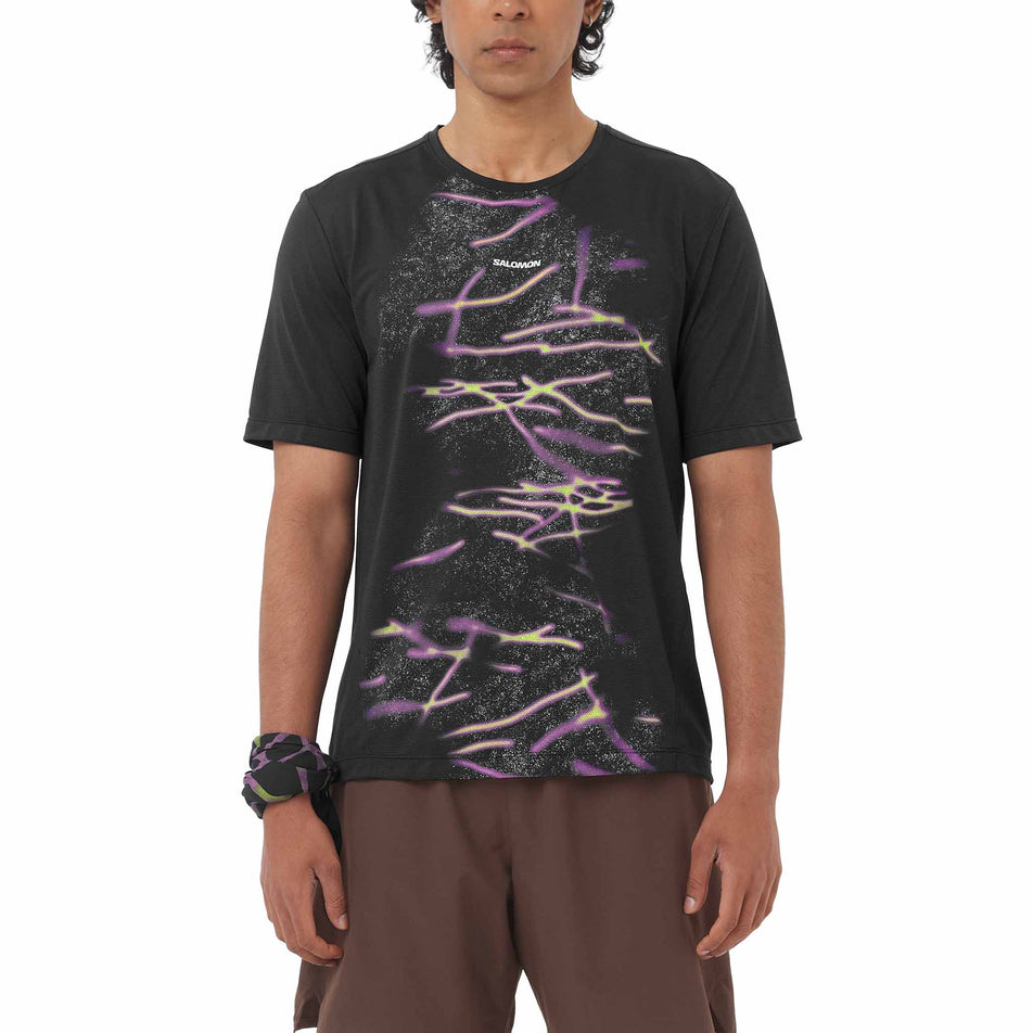 Front view of a model wearing the Salomon Men's SHKout Core SS Tee GFX in the Deep Black colourway.