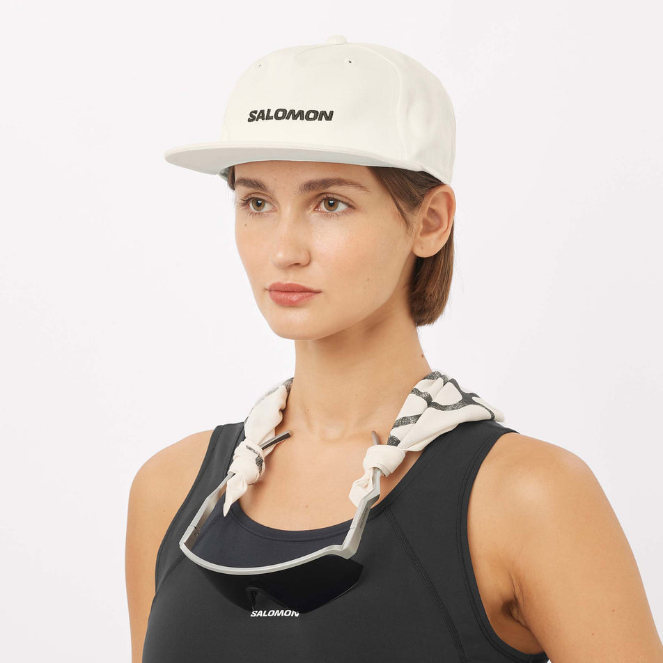 Front view of a model wearing the Salomon Unisex Logo Flat Cap in the Whisper White colourway.