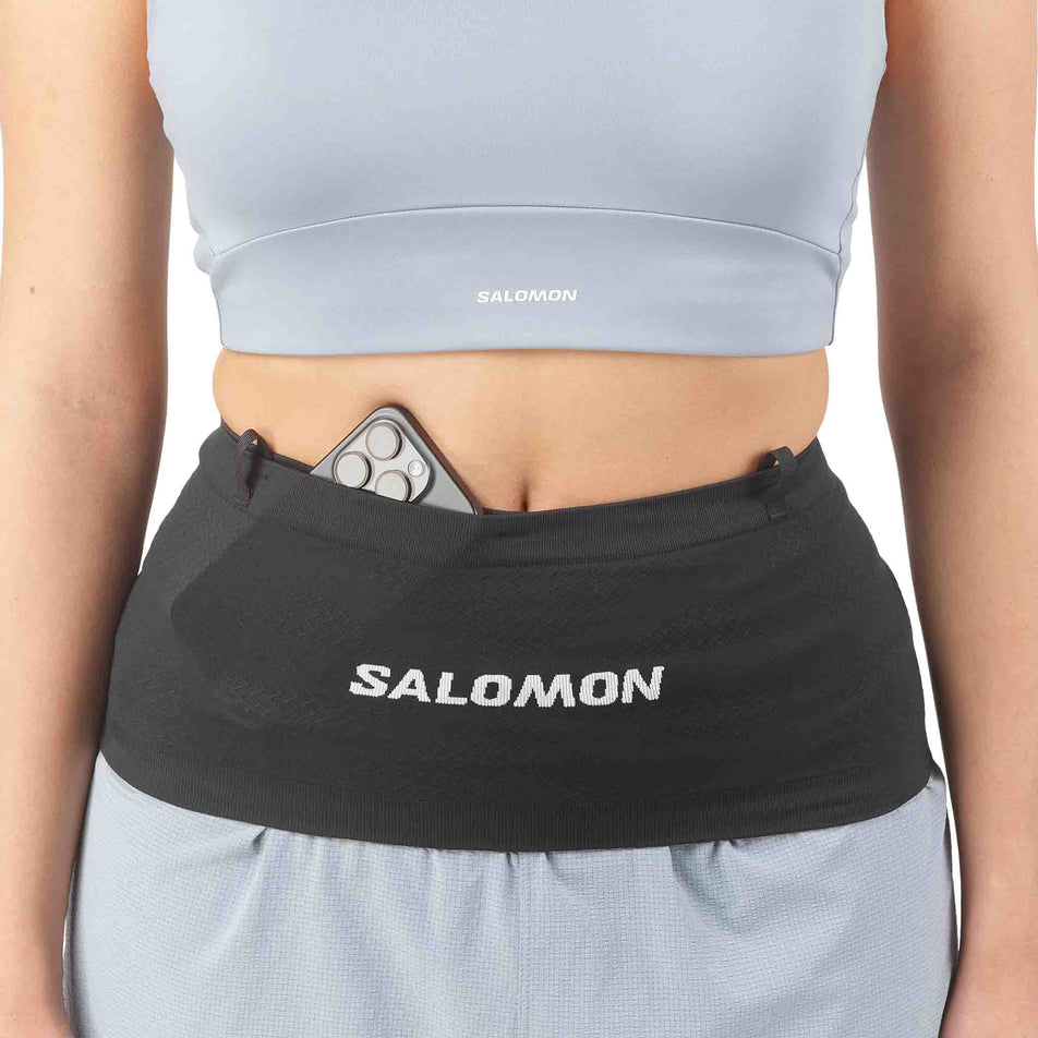 A phone stowed in the Salomon Unisex ADV Skin Seamless Belt in the Black/White colourway.