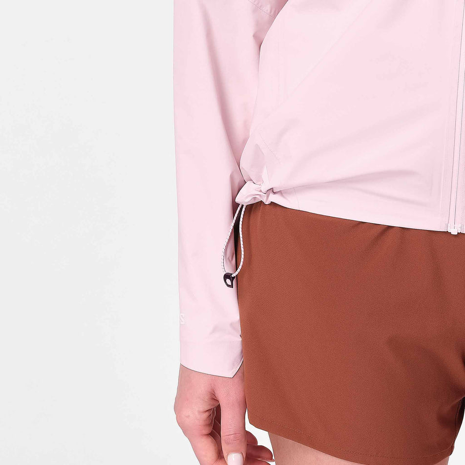 Close-up view of the adjustable toggle at the hem of the Salomon Women's Bonatti Pro Shell Jacket in the Icy Pink colourway.