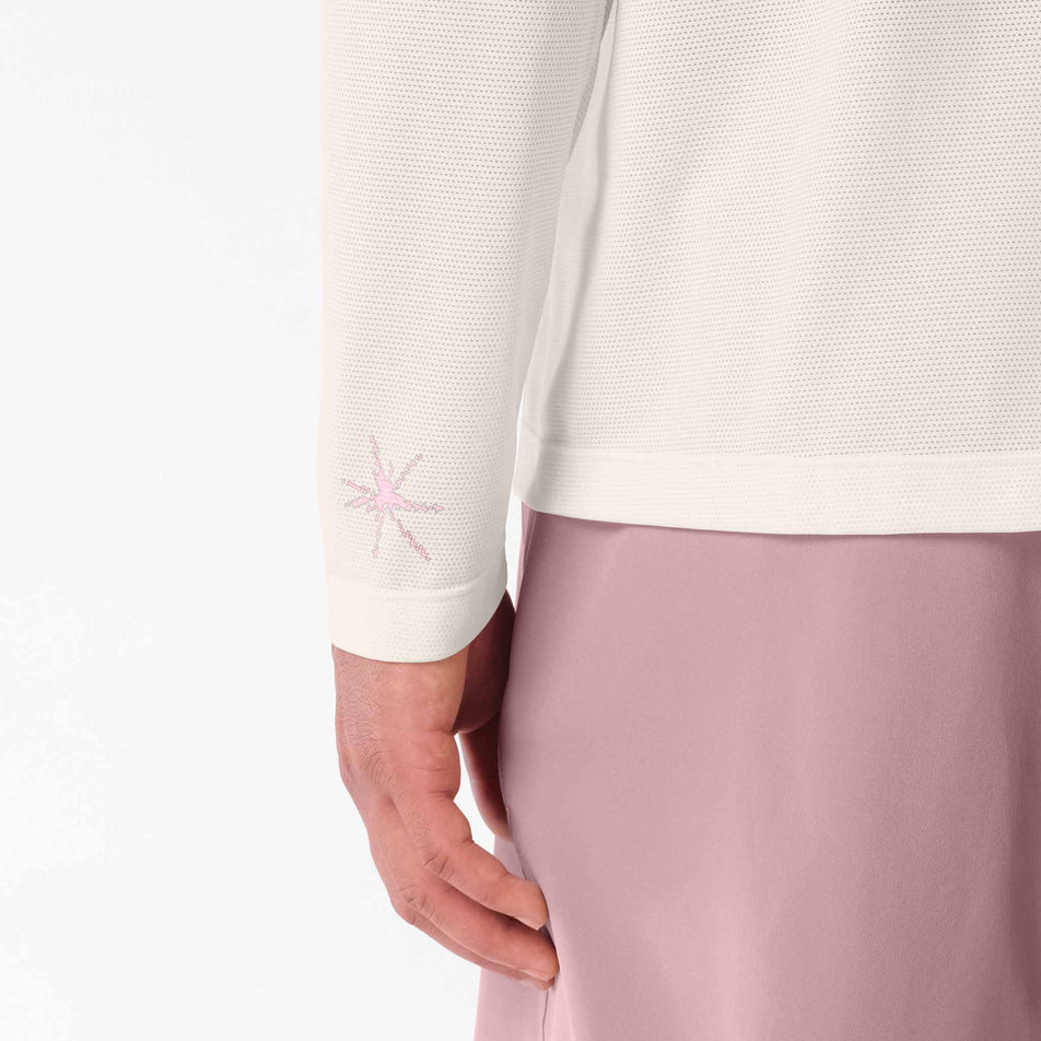 Close-up view of the graphic on the sleeve of the Salomon Men's Shakeout Core Graphic Long Sleeve T-Shirt in the Whisper White/Pink Frosting colourway.