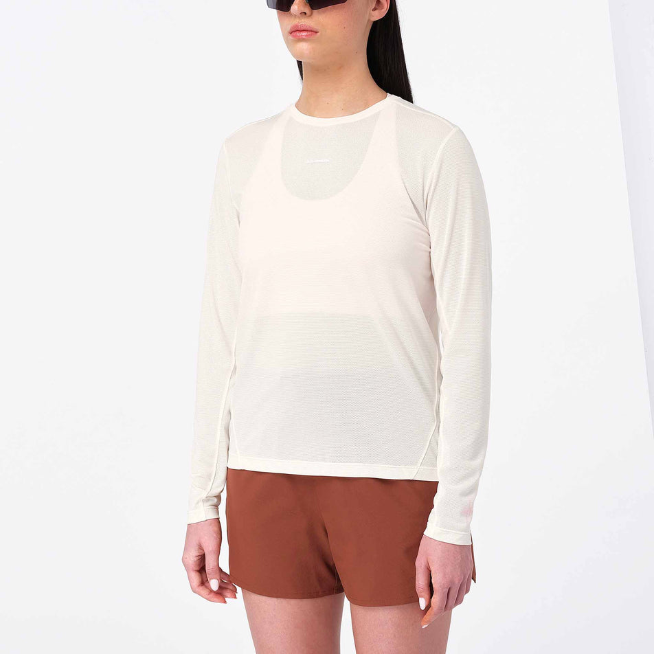Front view of a model wearing Salomon Women's Shakeout Core LS Tee GFX in the Whisper White/Pink Frosting colourway.