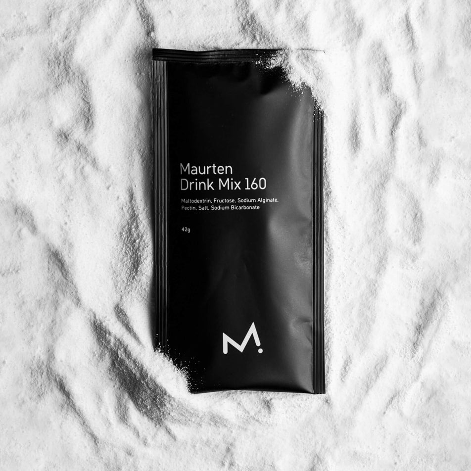 A 42 gram sachet of Maurten Drink Mix 160 resting on a white, powdery backdrop. (7077088133282)