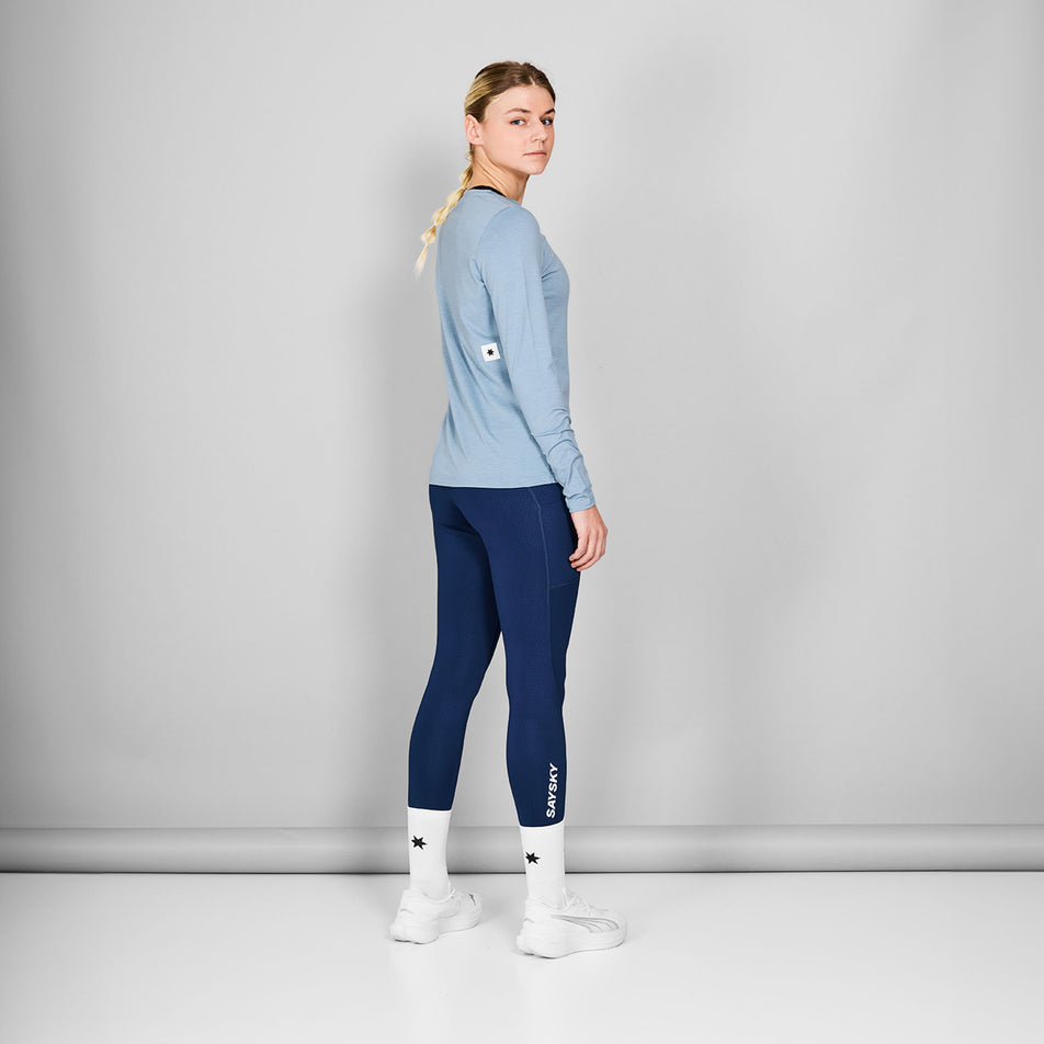 Back view of a model wearing the SAYSKY Women's Logo Pace Long Sleeve in the Blue Melange colourway. Model is also wearing tights, socks and shoes. (8602010452130)