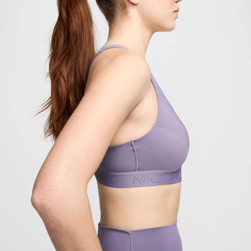 Side view of a model wearing a Nike Women's Indy High Support Padded Adjustable Sports Bra in the Daybreak/Daybreak colourway. (8215845961890)