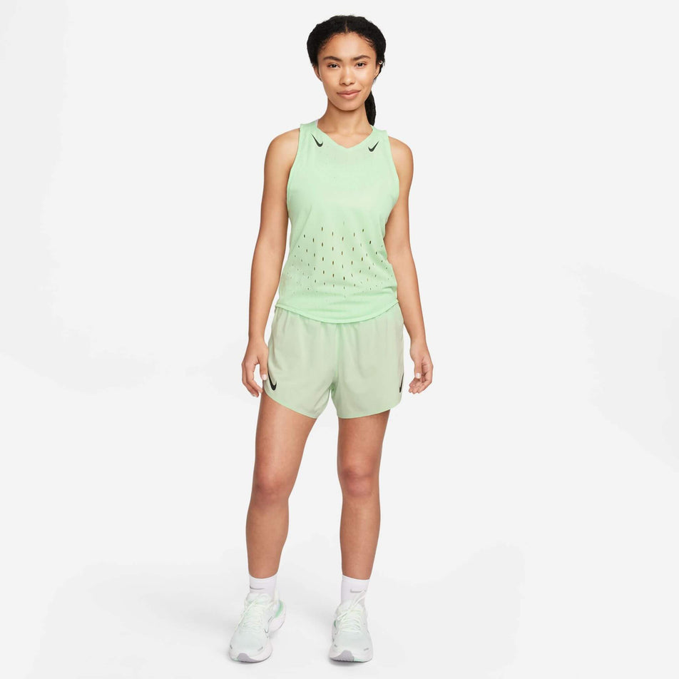 Front view of a model wearing the Women's AeroSwift Dri-FIT ADV Running Singlet in the Vapor Green/Black colourway. Model is also wearing Nike shorts, socks and shoes. (8186003357858)