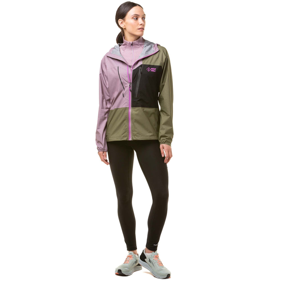 Front view of a model wearing a Ronhill Women's Tech Fortify Jacket in the Woodland/Stardust/Black. Model is also wearing black running tights and grey running shoes. (8024348328098)