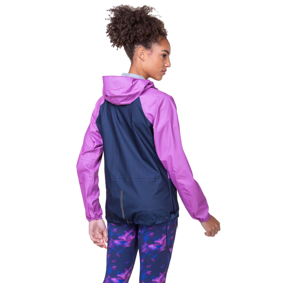 Back view of a model wearing the Women's Tech Fortify Jacket in the Dark Navy/Fuchsia colourway. Model is also wearing Ronhill leggings. (8160855752866)
