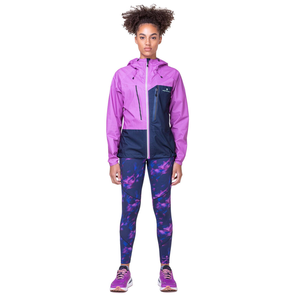Front view of a model wearing the Women's Tech Fortify Jacket in the Dark Navy/Fuchsia colourway. Model is also wearing Ronhill leggings and Altra running shoes.. (8160855752866)