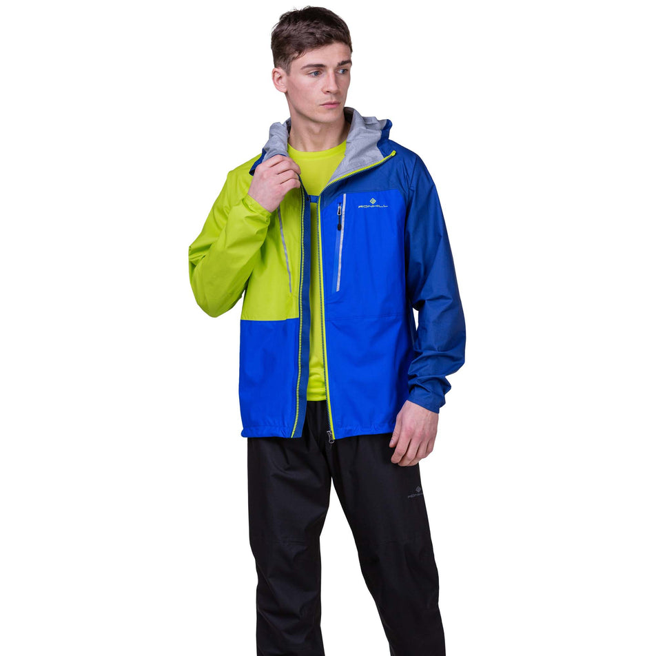 Front view of a model wearing the Ronhill Men's Tech Fortify Jacket in the Ocean/Citrus colourway. Model is also wearing Ronhill trousers. (8160892911778)