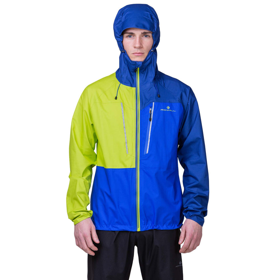 Front view of a model wearing the Ronhill Men's Tech Fortify Jacket in the Ocean/Citrus colourway, with the hood up. (8160892911778)
