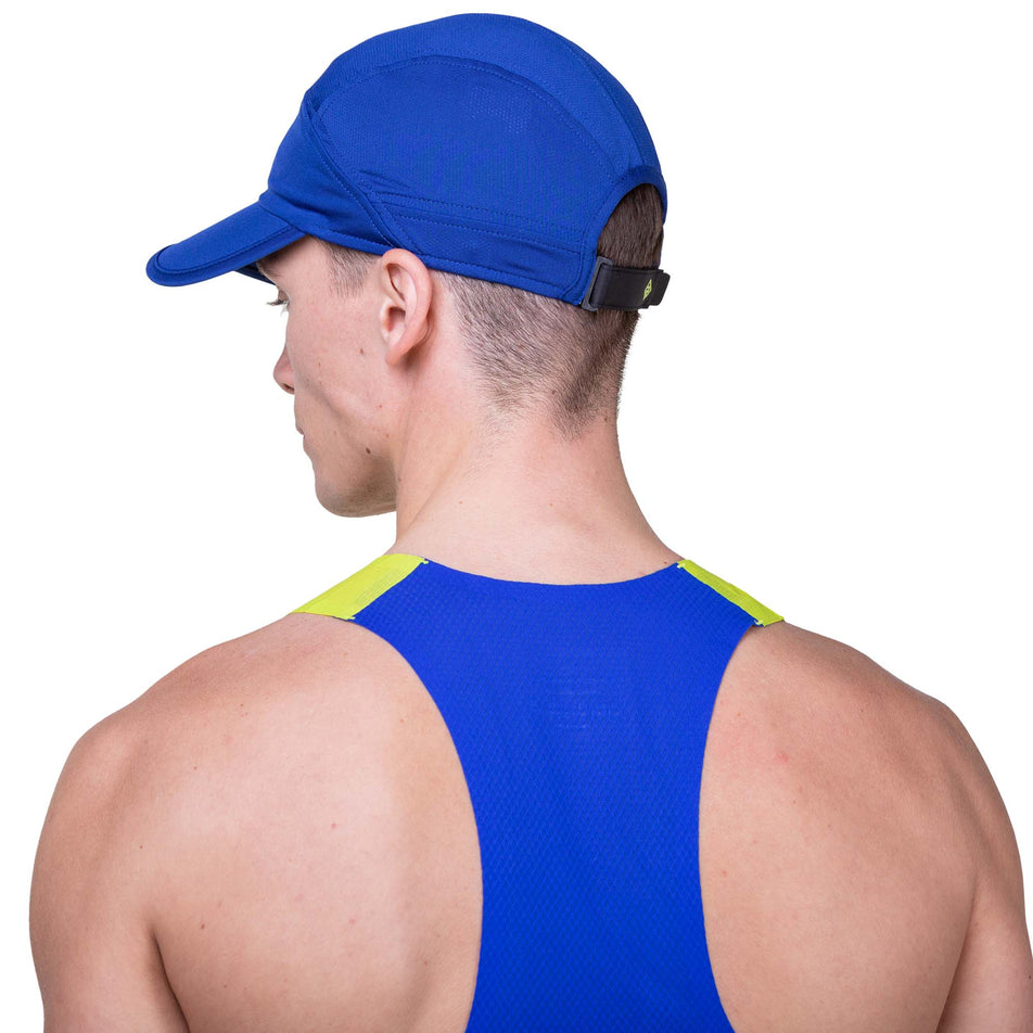 Back view of a model wearing a Ronhill Unisex Air-Lite Split Cap in the Ocean/Citrus colourway. Model is also wearing a Ronhill vest. (8160950223010)
