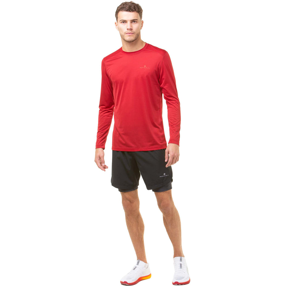 Front view of a model wearing a Ronhill Men's Tech L/S Tee in the Jam/Flame colourway. Model is also wearing Ronhill shorts and Altra shoes. (8048653467810)