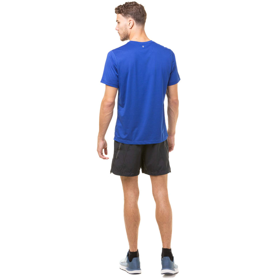 Back view of a model wearing a Ronhill Men's Tech S/S Tee in the Dark Cobalt/Flame colourway. Model is also wearing Ronhill running shorts and Altra running shoes. (8048115253410)