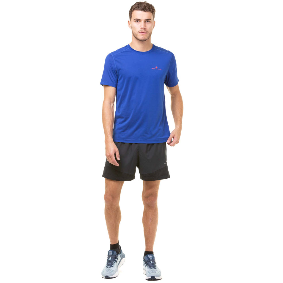Front view of a model wearing a Ronhill Men's Tech S/S Tee in the Dark Cobalt/Flame colourway. Model is also wearing Ronhill running shorts and Altra running shoes. (8048115253410)