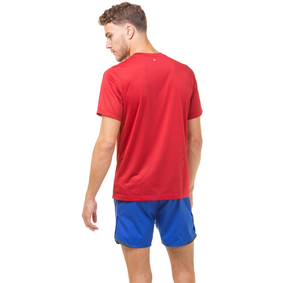 Back view of a model wearing a Ronhill Men's Tech S/S Tee in the Jam/Flame colourway. Model is also wearing a pair of Ronhill running shorts. (8048107978914)